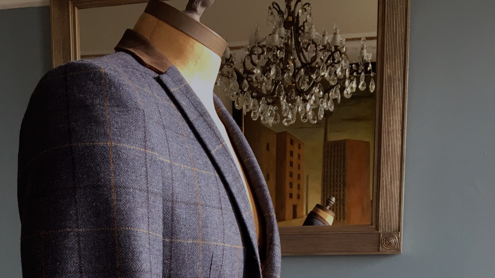 A windowpane check jacket on a mannequin beside a gilt mirror