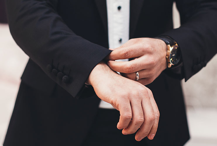 A man fastening the cuff of a dark tailored suit