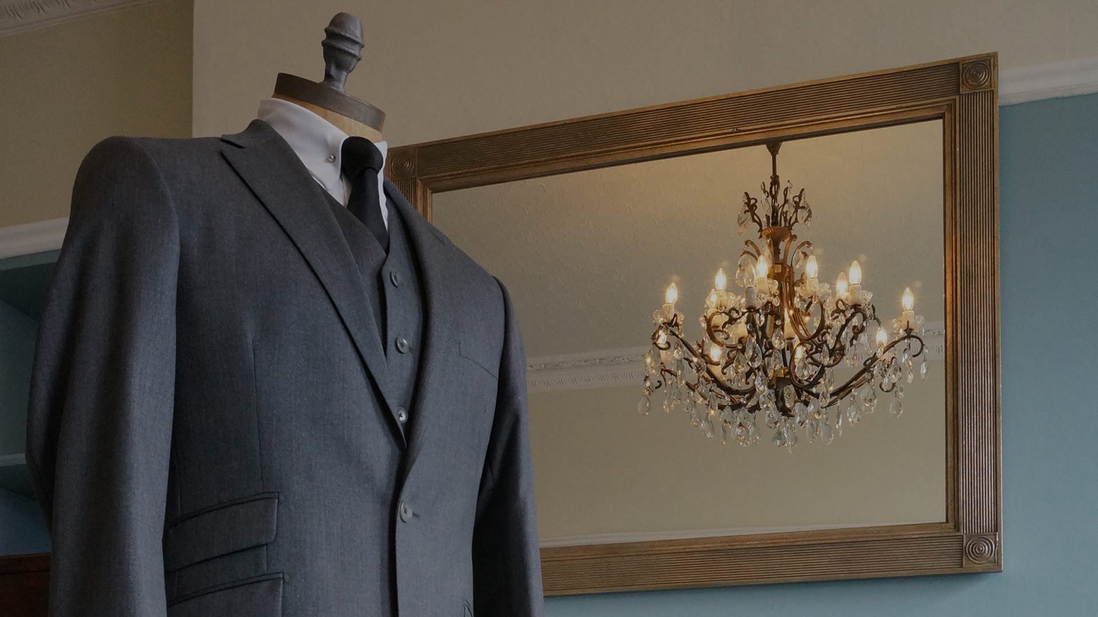 A hand-made British Tailoring Co suit on a mannequin beside a gilt mirror
