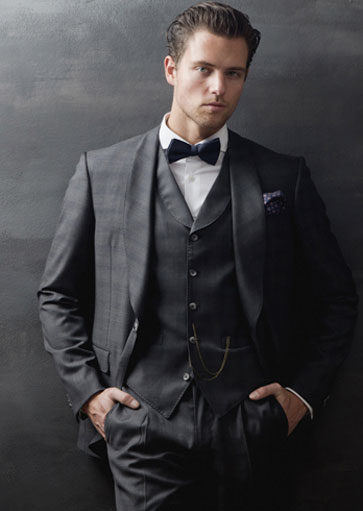 A man wearing a finished three-piece suit and bow tie